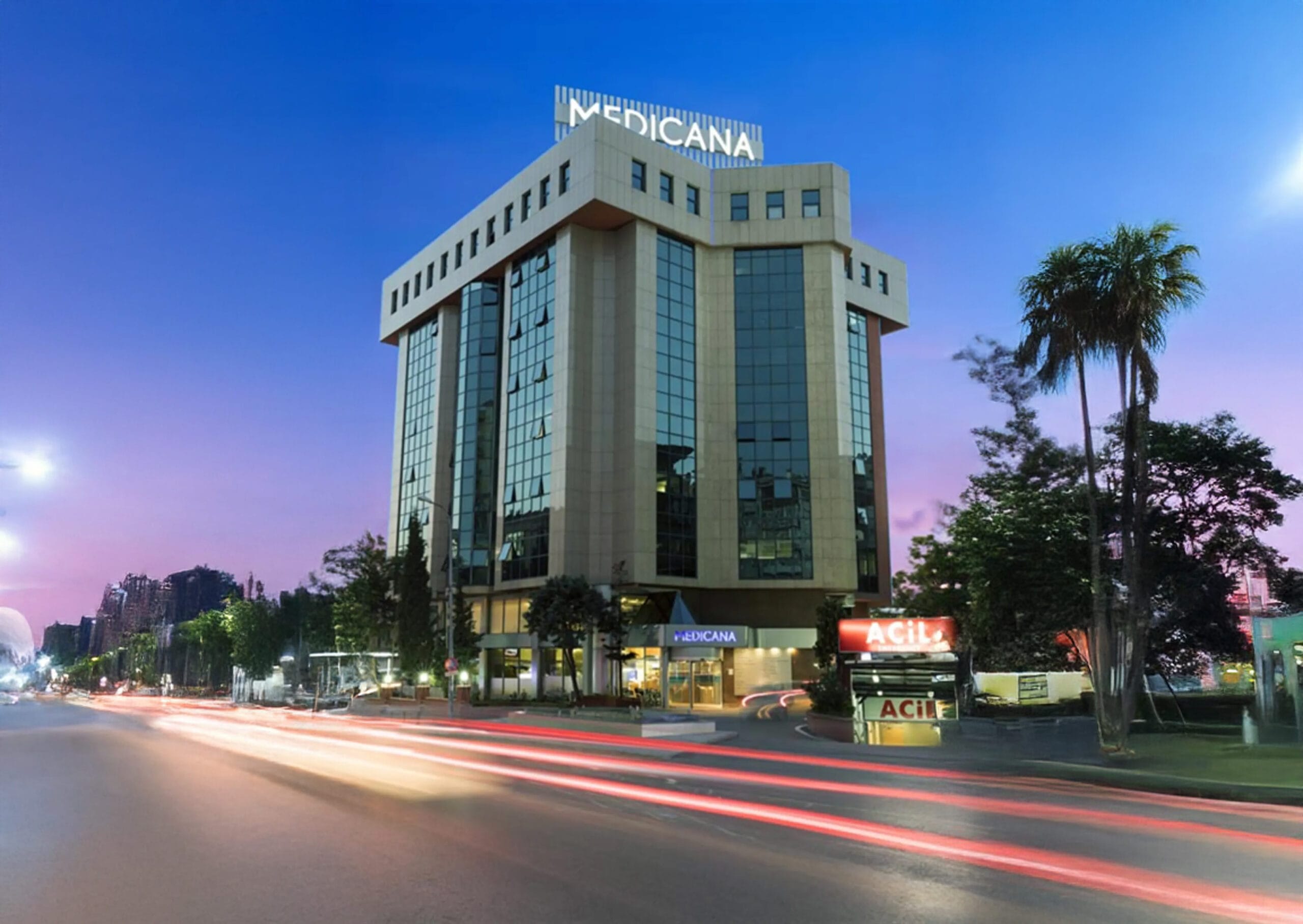 Gece manzarasında aydınlatılan Medicana hastane binası ve çevresindeki yol hareketliliği.