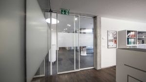 Haberler & Blog 18 Ofis iç mekanı, cam kapı ve acil çıkış tabelası. Modern tasarımlı ve aydınlık bir ofis girişi.