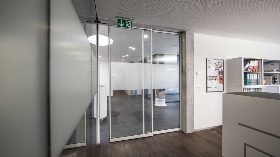 Ofis iç mekanı, cam kapı ve acil çıkış tabelası. Modern tasarımlı ve aydınlık bir ofis girişi.