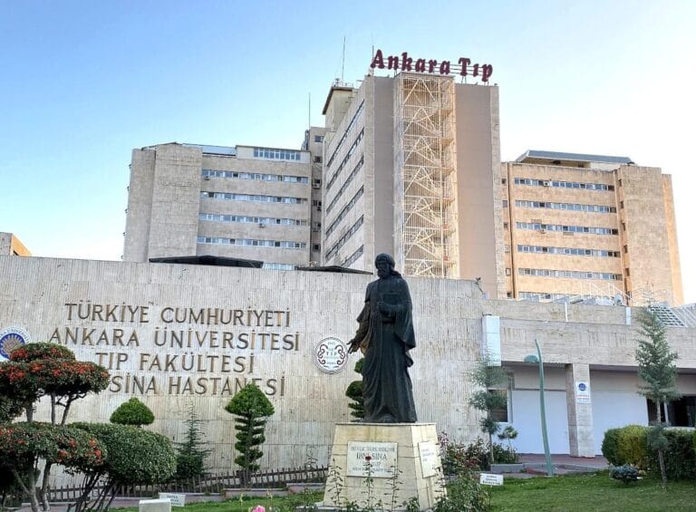 Ankara Üniversitesi Tıp Fakültesi İbni Sina Hastanesi binası ve önünde heykel.